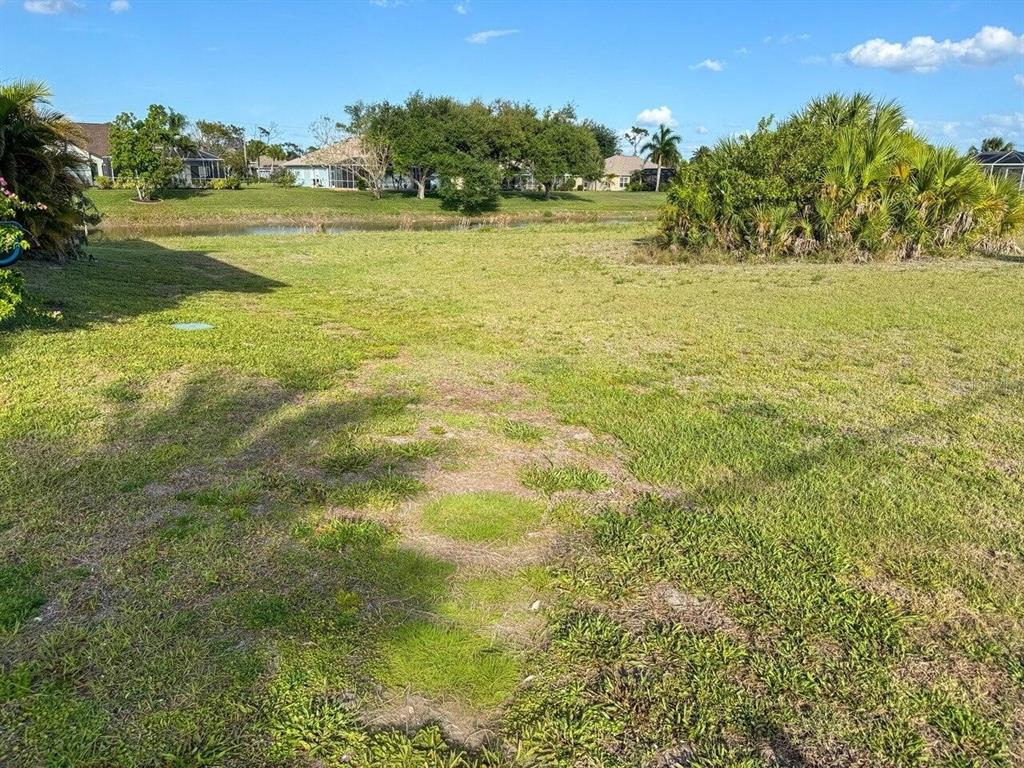 A grassy vacant lot overlooks a small pond with houses in the background — 743 ROTONDA CIRCLE, ROTONDA WEST, FL