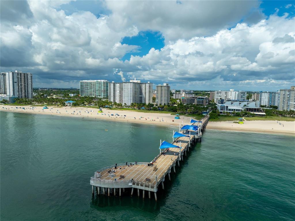 An aerial view shows a long pier extending into the ocean near a sandy beach — 133 N Pompano Beach Boulevard # 105, Pompano Beach FL 33062, POMPANO BEACH, FL