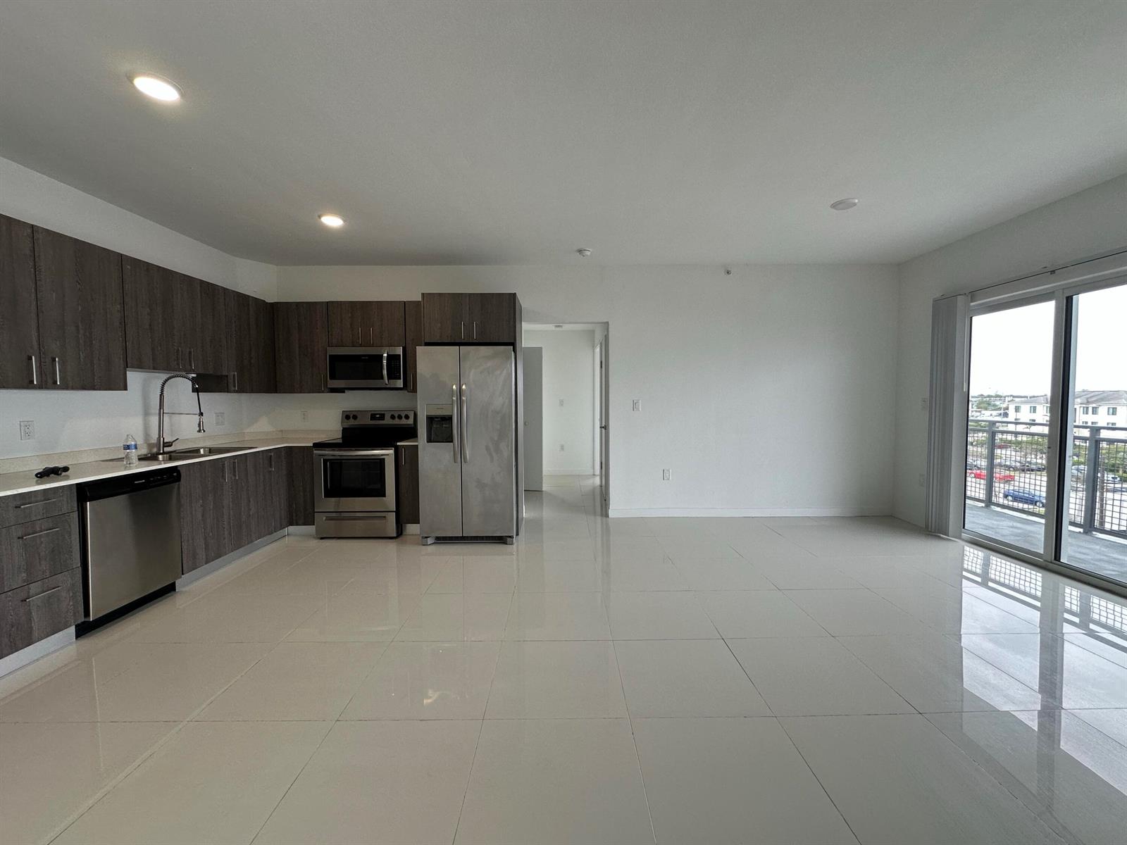 A modern kitchen with dark wood cabinets and stainless steel appliances opens to a living area — 25885 S Dixie Highway, Homestead FL 33032, HOMESTEAD, FL