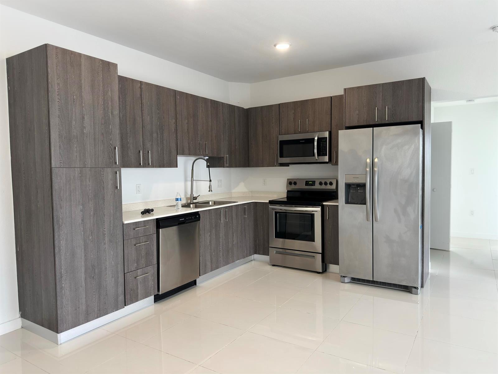 A kitchen features dark wood cabinets, stainless steel appliances, and white tile flooring — 25885 S Dixie Highway, Homestead FL 33032, HOMESTEAD, FL