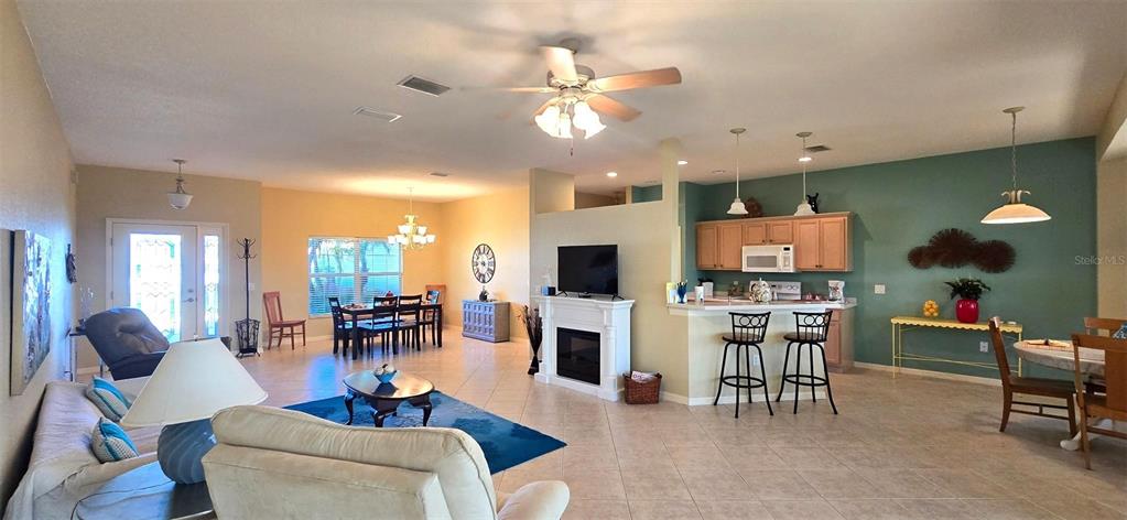 An open-concept living and dining area features tile flooring, a fireplace, and a kitchen island — 4023 ASHTON CLUB DRIVE, LAKE WALES, FL