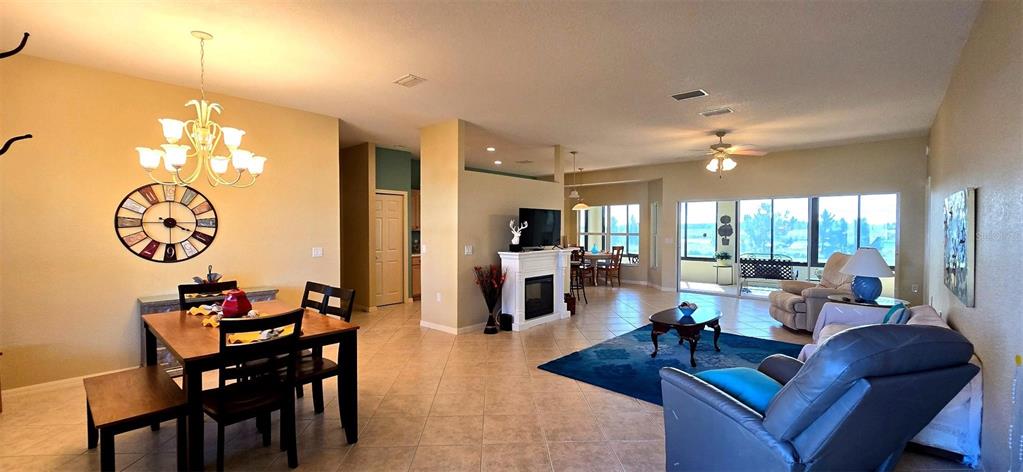 An open-concept living and dining area features tile flooring, a fireplace, and large windows — 4023 ASHTON CLUB DRIVE, LAKE WALES, FL