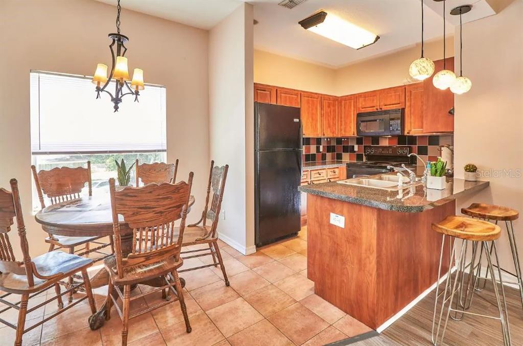 A kitchen with wood cabinets and a dining area with a round wooden table — 800 E BAKER STREET, TAMPA, FL