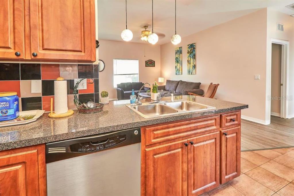 A kitchen with granite countertops and stainless steel appliances overlooks an open-concept living area — 800 E BAKER STREET, TAMPA, FL