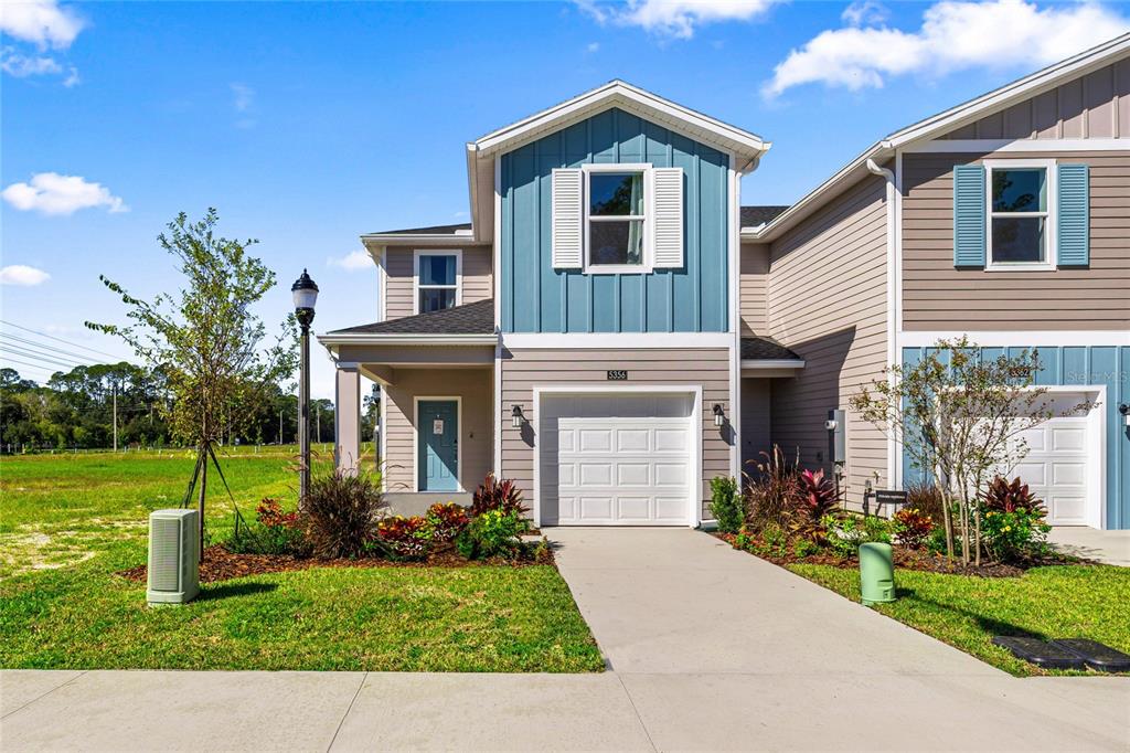 A two-story suburban townhouse with blue vertical siding, a white garage, and a concrete driveway — 5422 NW 22ND DRIVE, GAINESVILLE, FL