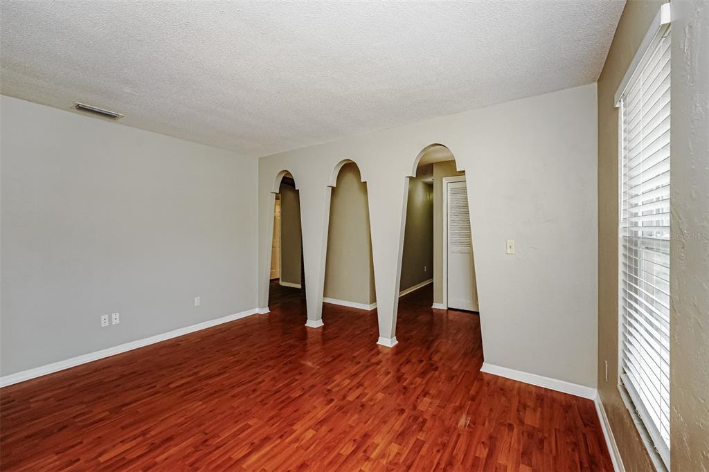 A room with wood-look flooring and three arched openings leading to other areas — 1402 FINDLAY STREET, DELTONA, FL