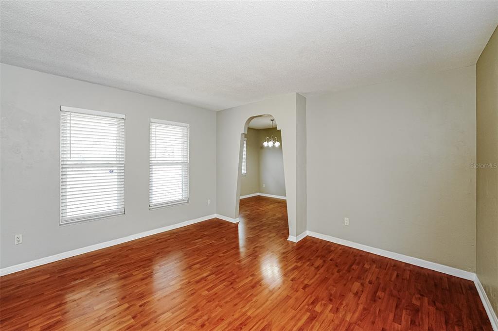 An empty room with wood-look flooring and an arched doorway leading to another space — 1402 FINDLAY STREET, DELTONA, FL