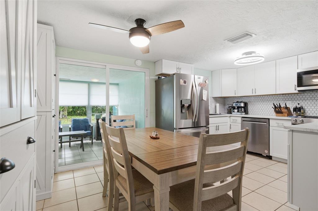 A kitchen and dining area with white cabinets, stainless steel appliances, and a sliding glass door — 60 S LINCOLN AVENUE, BEVERLY HILLS, FL