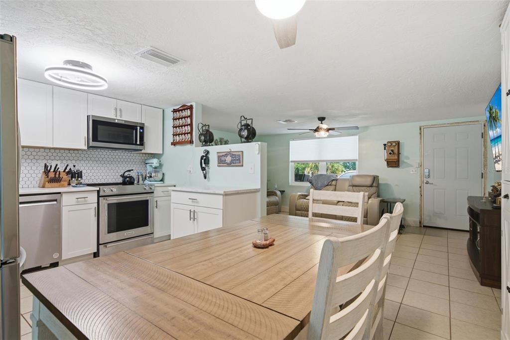 A kitchen and dining area with white cabinets, stainless steel appliances, and a wooden table — 60 S LINCOLN AVENUE, BEVERLY HILLS, FL