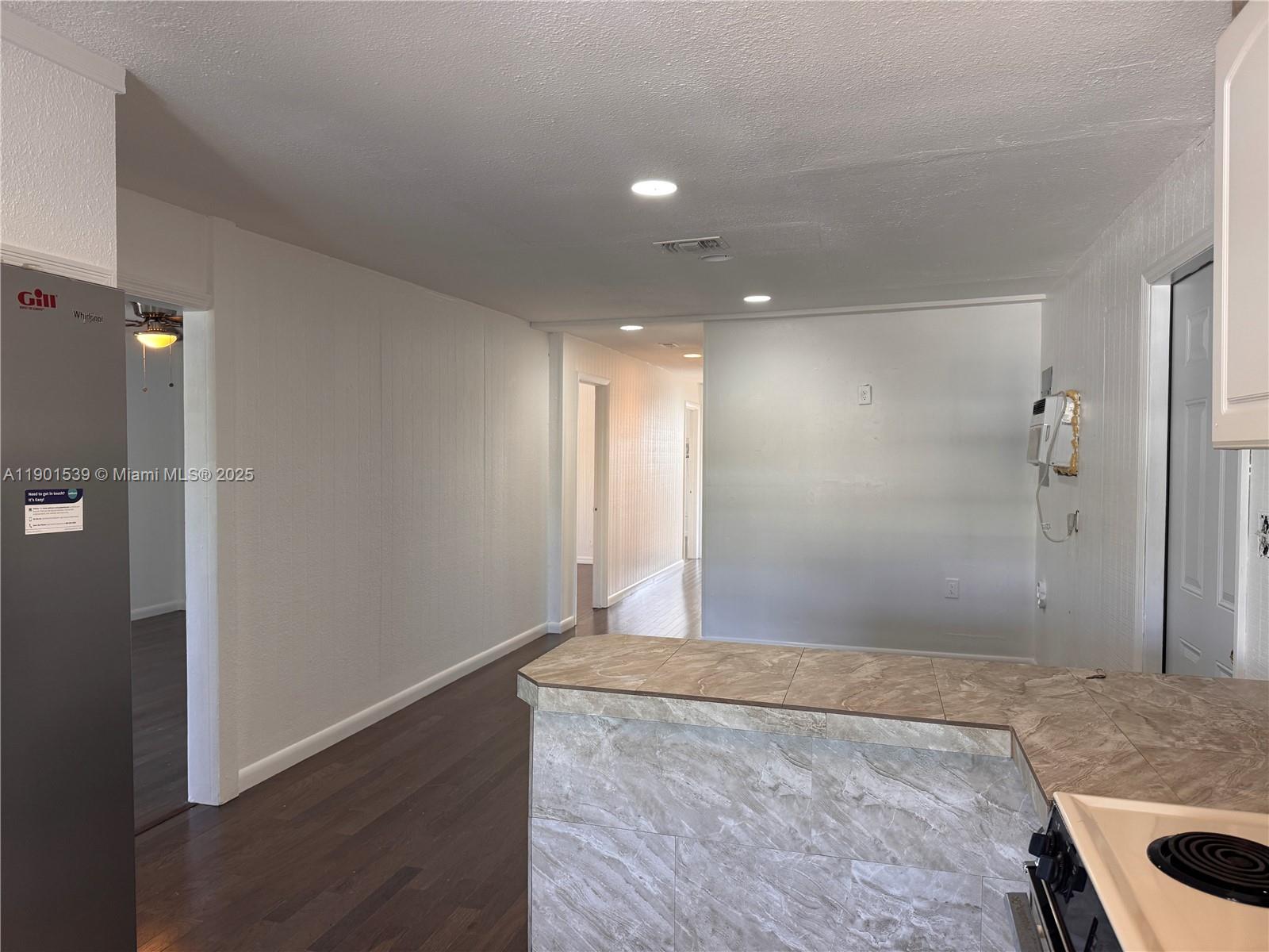 A kitchen with a tiled peninsula counter overlooks a hallway with dark wood flooring — 969 Plantation Rd, Key Largo FL 33037, KEY LARGO, FL