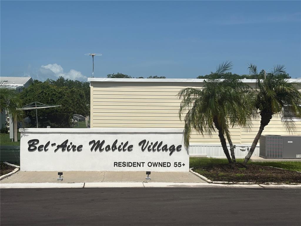 A sign for Bel-Aire Mobile Village stands in front of a light-colored mobile home — 11300 124TH AVENUE UNIT 81, LARGO, FL
