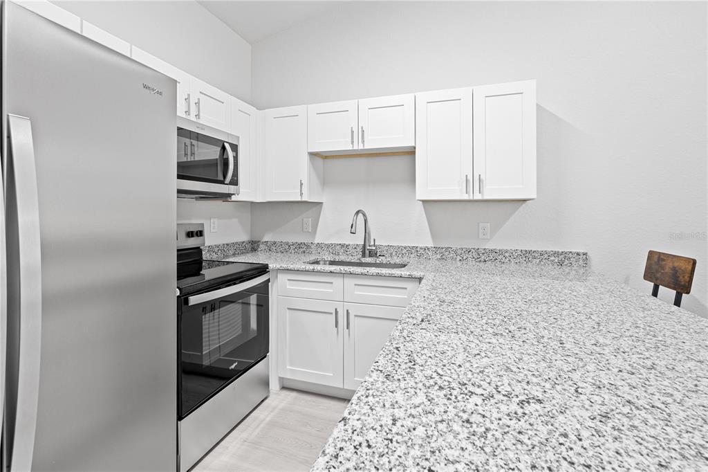 A kitchen features white cabinets, granite countertops, stainless steel appliances, and a sink — 607 SE 4TH DRIVE UNIT A, WILLISTON, FL