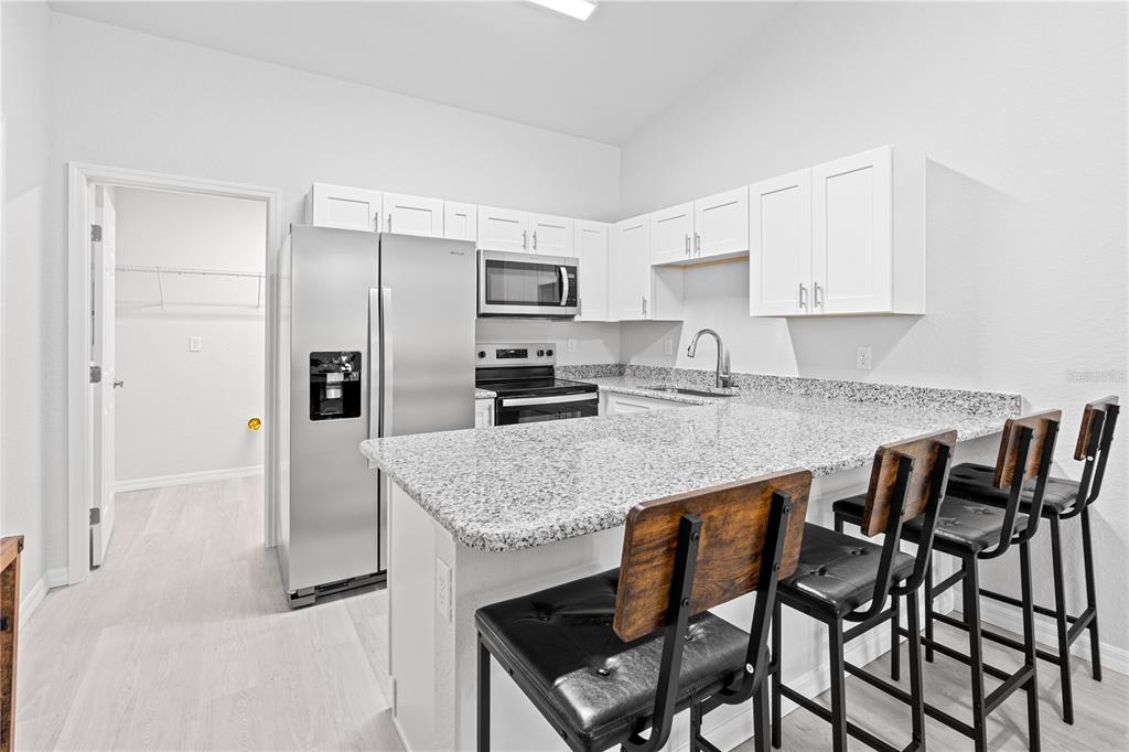 A kitchen features white cabinets, granite countertops, stainless steel appliances, and a breakfast bar — 607 SE 4TH DRIVE UNIT A, WILLISTON, FL