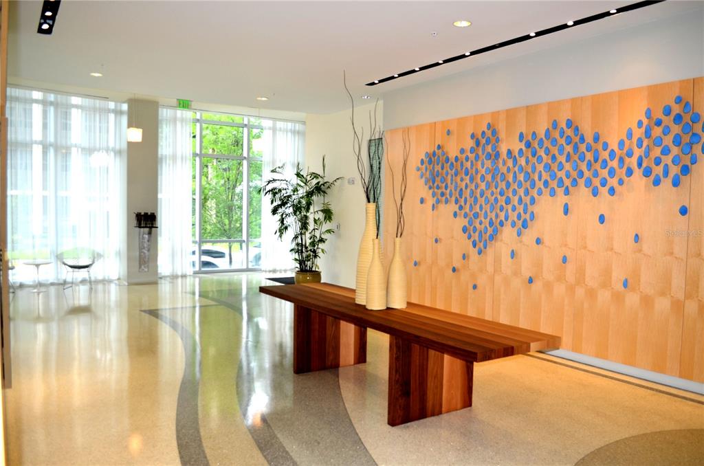 A modern lobby features a wooden console table, blue wall art, and polished terrazzo floors — 150 E ROBINSON STREET UNIT 2012, ORLANDO, FL