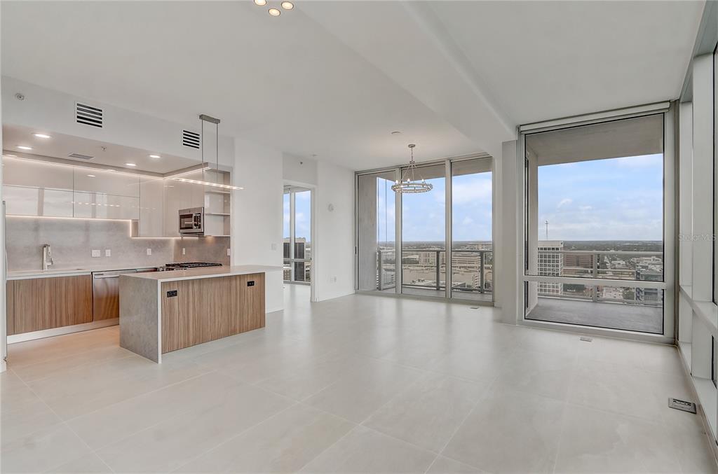 A modern open-concept kitchen and living area with floor-to-ceiling windows and city views — 150 E ROBINSON STREET UNIT 2012, ORLANDO, FL