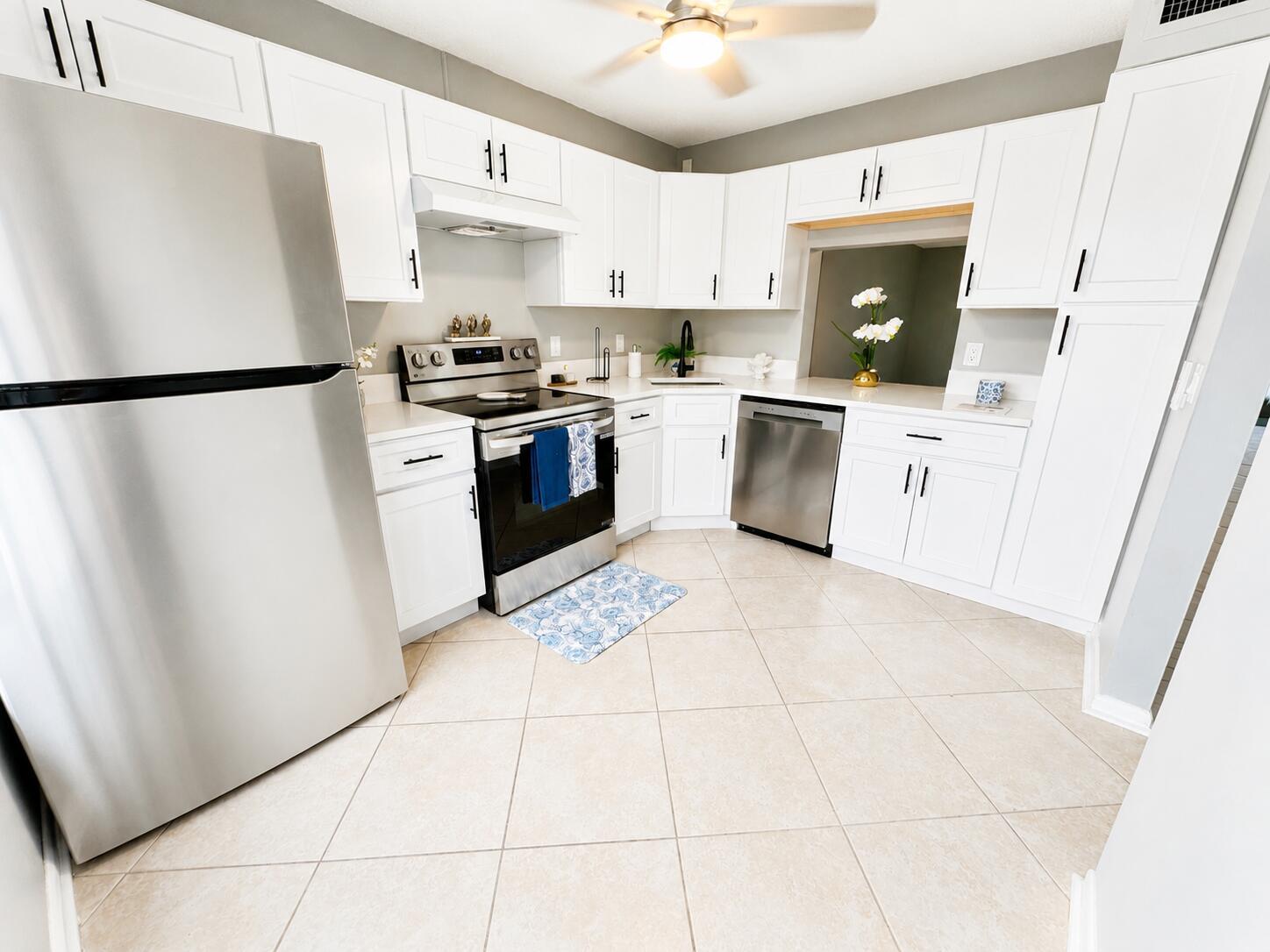 A kitchen with white cabinets, stainless steel appliances, and light-colored tile flooring — 222 Foxtail Drive, FL 33415, FL