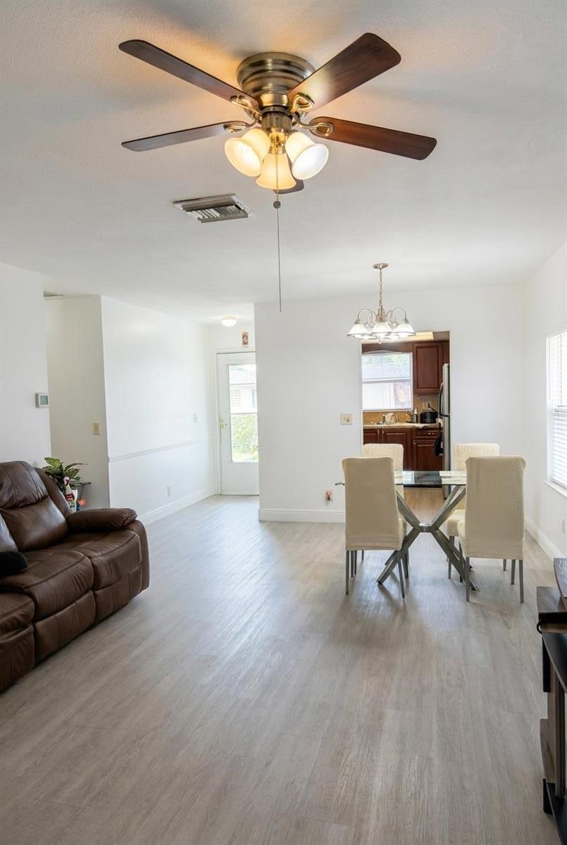 A living and dining area with light wood-look flooring, a ceiling fan, and white walls — 2898 Ashley Dr Drive E # C, West Palm Beach FL 33415, WEST PALM BEACH, FL