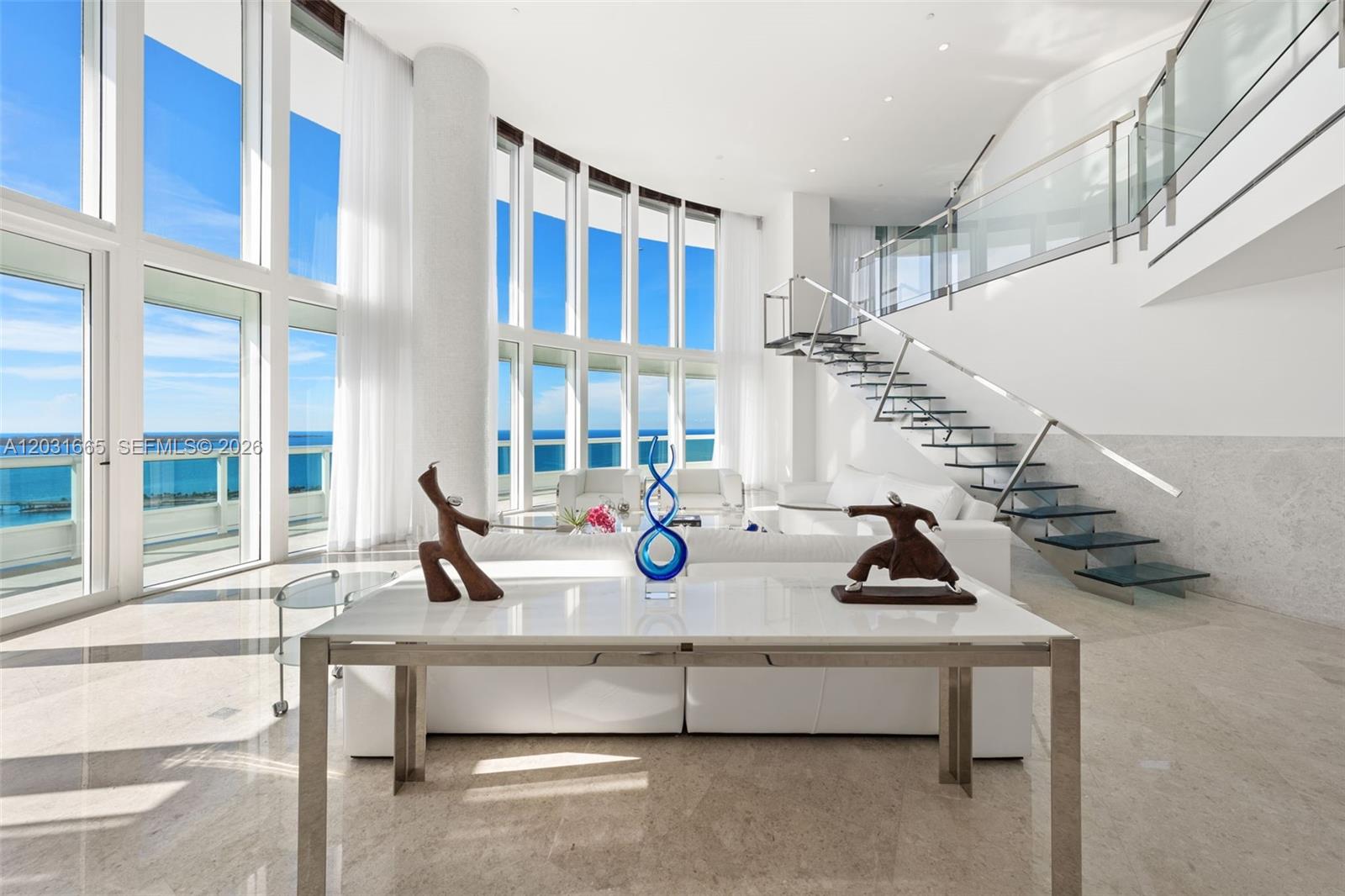 A bright, modern living room features floor-to-ceiling windows, a glass staircase, and ocean views — 1643 Brickell Ave # 4102, Miami FL 33129, MIAMI, FL