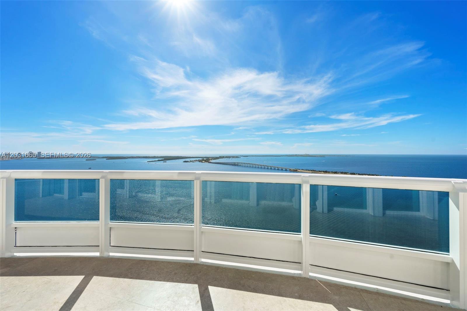 A balcony with a white railing overlooks a large body of water and a bridge — 1643 Brickell Ave # 4102, Miami FL 33129, MIAMI, FL