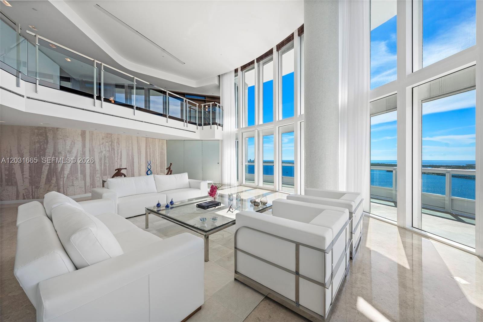 A bright, double-height living room features white furniture, a glass coffee table, and floor-to-ceiling windows — 1643 Brickell Ave # 4102, Miami FL 33129, MIAMI, FL