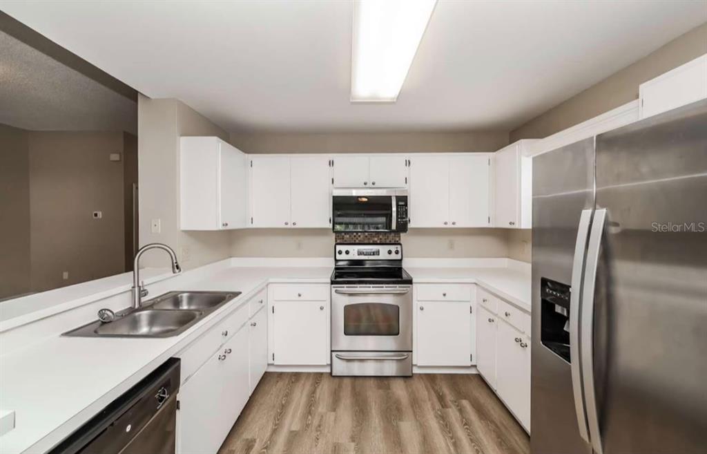 A kitchen with white cabinets, stainless steel appliances, and light wood-look flooring — 1131 EVENING TRAIL DRIVE, WESLEY CHAPEL, FL
