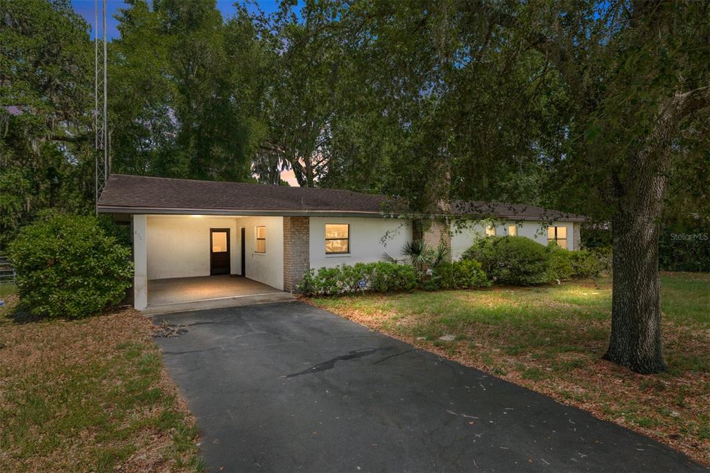 A single-story house with a carport, a paved driveway, and mature trees in the yard — 4367 S US 301, BUSHNELL, FL