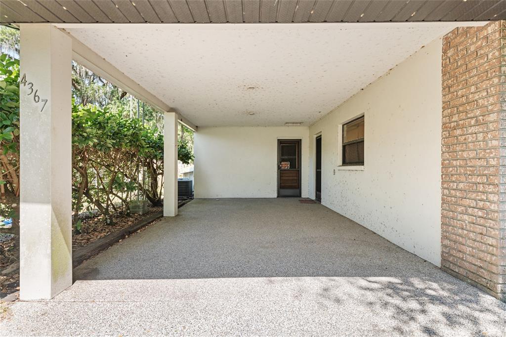 A covered concrete carport features a brick wall, two doorways, and a support pillar — 4367 S US 301, BUSHNELL, FL