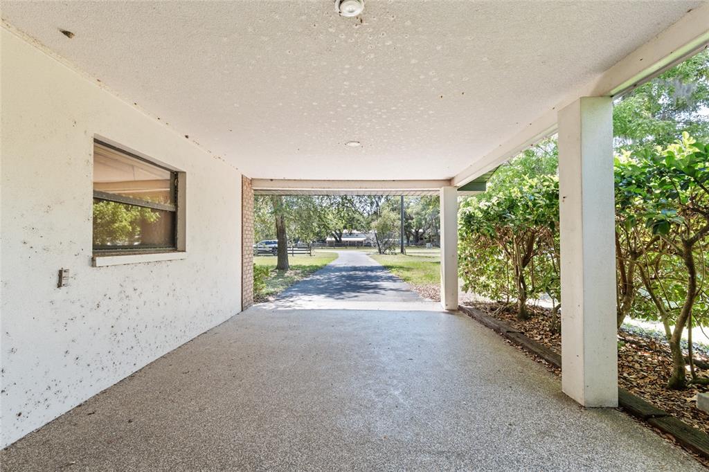 A covered carport with a textured ceiling, concrete floor, and a view of the driveway — 4367 S US 301, BUSHNELL, FL