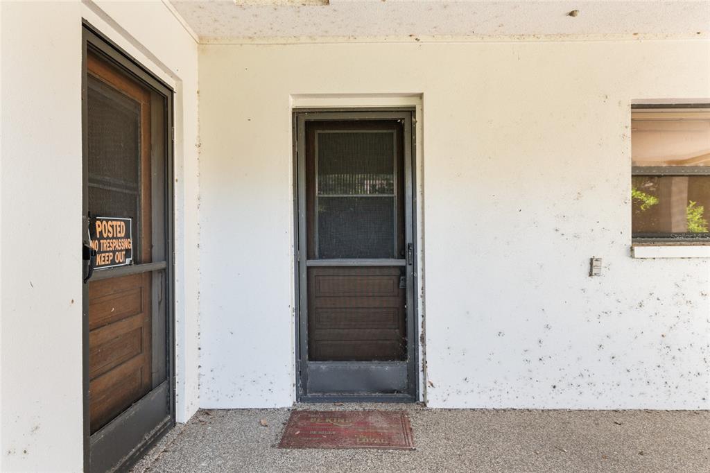 A covered porch features two screen doors and a window on a white exterior wall — 4367 S US 301, BUSHNELL, FL