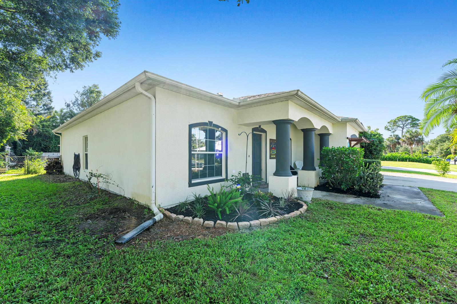 A single-story house with a stucco exterior, dark columns, and a landscaped front garden — 1302 Coverbrook Lane, Sebastian FL 32958, SEBASTIAN, FL