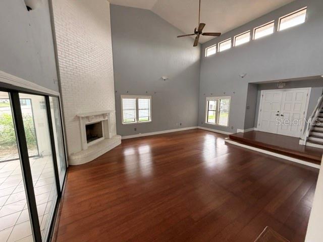 A spacious living room features hardwood floors, a white brick fireplace, and high vaulted ceilings — 7 CLEE CT, PALM COAST, FL