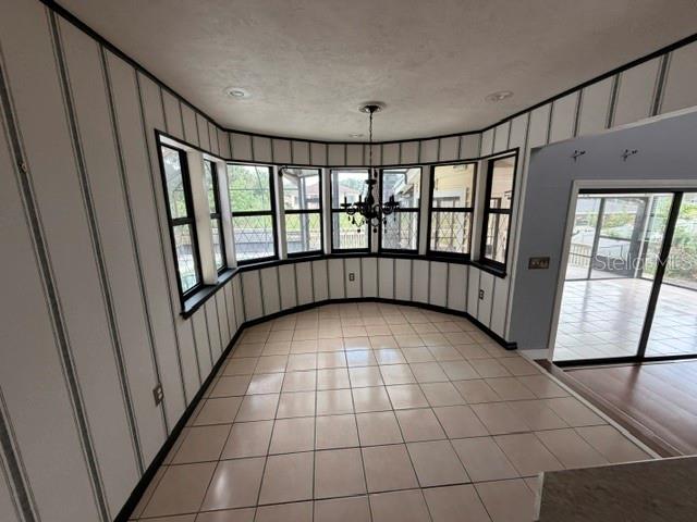 A dining area features striped wallpaper, a tile floor, a chandelier, and large bay windows — 7 CLEE CT, PALM COAST, FL