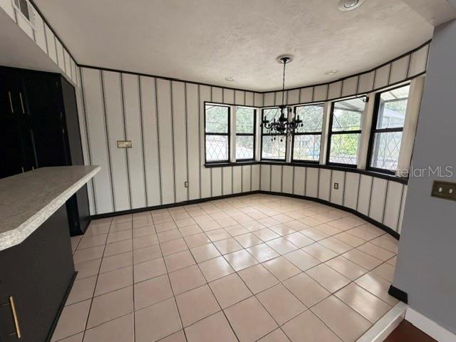 A dining area features striped wallpaper, tile flooring, a chandelier, and a bay window — 7 CLEE CT, PALM COAST, FL