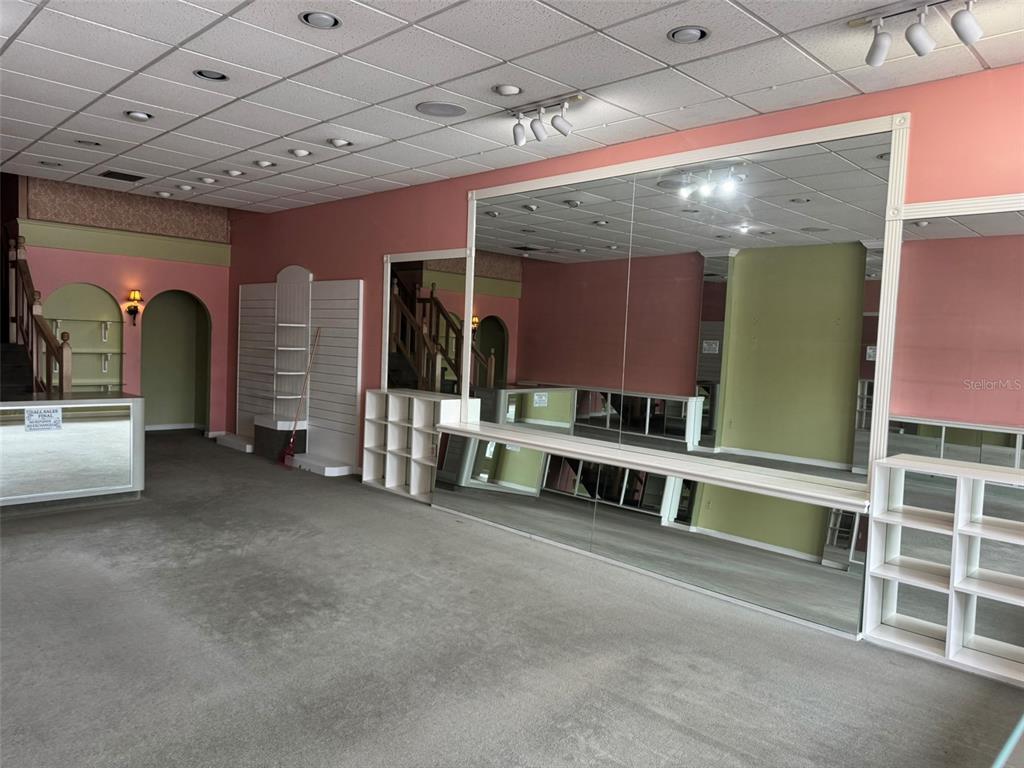 A commercial retail space features pink walls, gray carpeting, mirrored walls, and built-in shelving — 3411 SW 34TH STREET, GAINESVILLE, FL