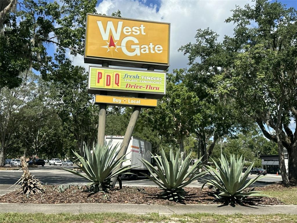 A sign for West Gate and PDQ stands behind three large agave plants outdoors — 3411 SW 34TH STREET, GAINESVILLE, FL