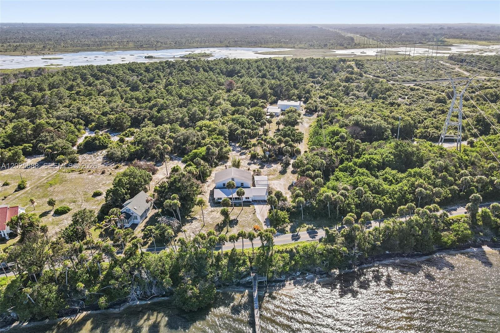 An aerial view shows two houses near a shoreline with a dock and power lines — 7803 S Indian River, Fort Pierce FL 34982, FORT PIERCE, FL