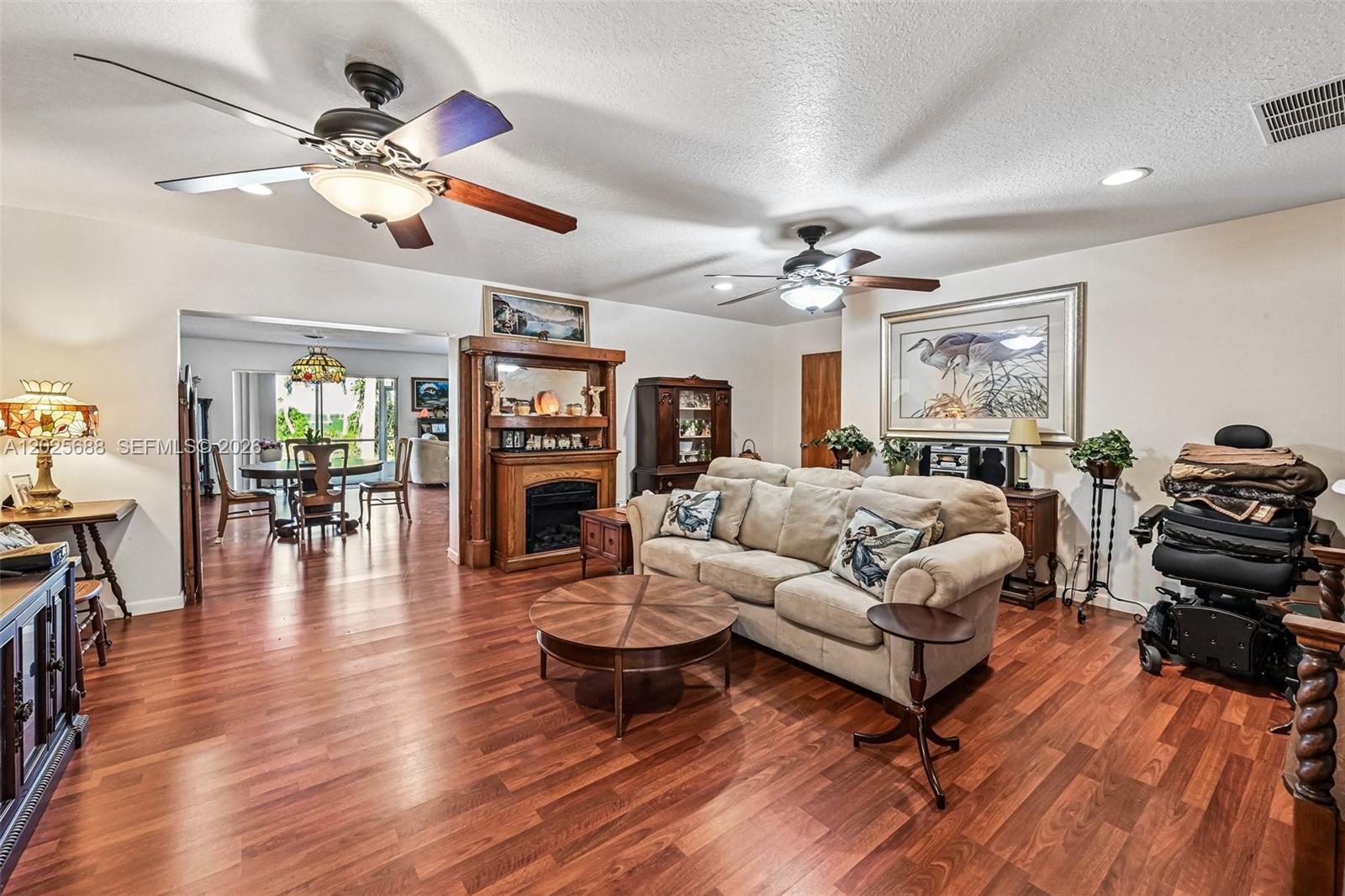 A living room features hardwood floors, a fireplace, two ceiling fans, and a beige sofa — 7803 S Indian River, Fort Pierce FL 34982, FORT PIERCE, FL
