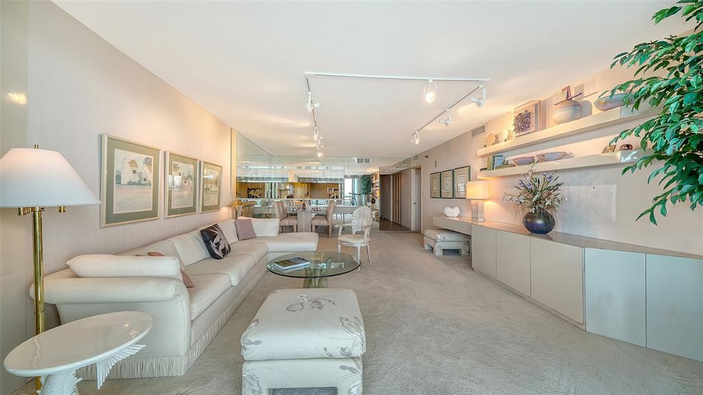 A living room features a white sectional sofa, glass coffee table, and built-in wall shelving — 988 BLVD OF THE ARTS UNIT 1411, SARASOTA, FL