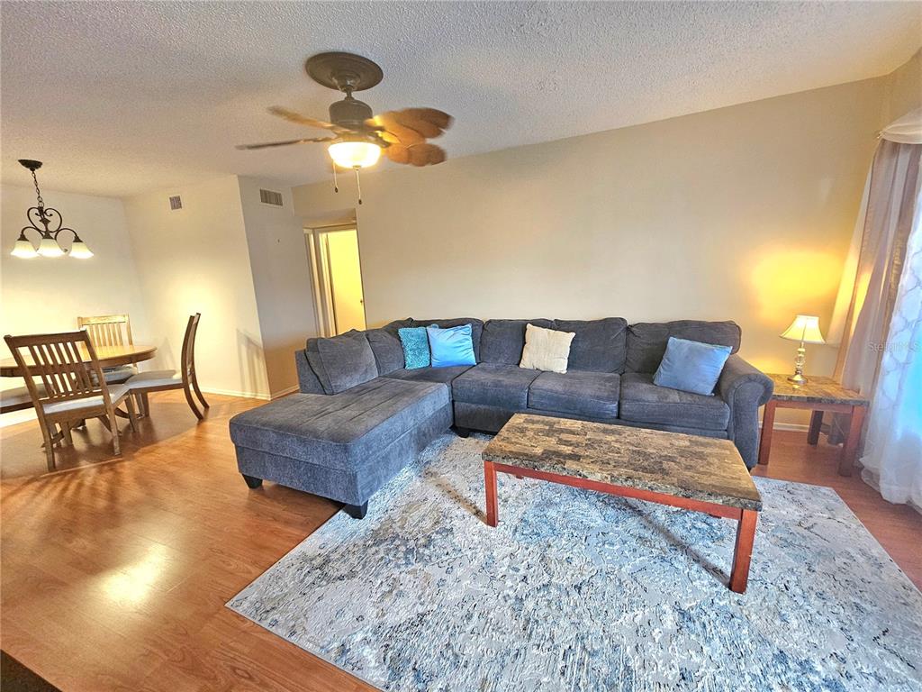 A living room with a sectional sofa, coffee table, and adjacent dining area — 2469 FRANCISCAN DRIVE UNIT 59, CLEARWATER, FL