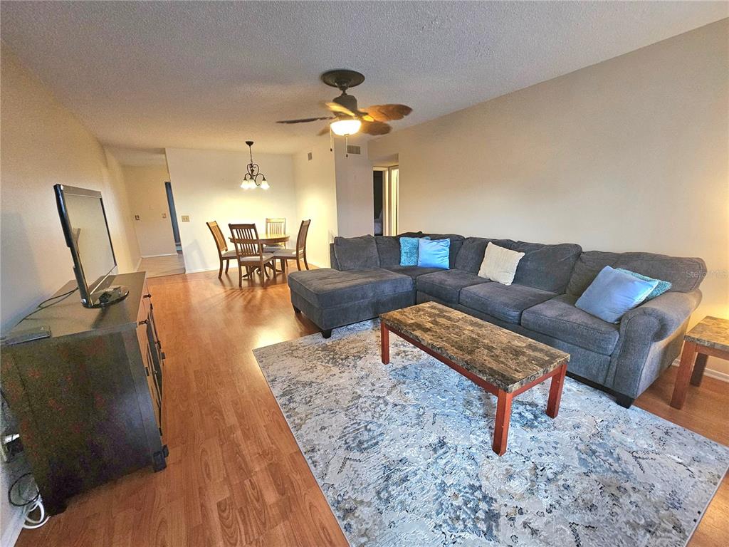 A living room with a gray sectional sofa, area rug, and an adjacent dining area — 2469 FRANCISCAN DRIVE UNIT 59, CLEARWATER, FL