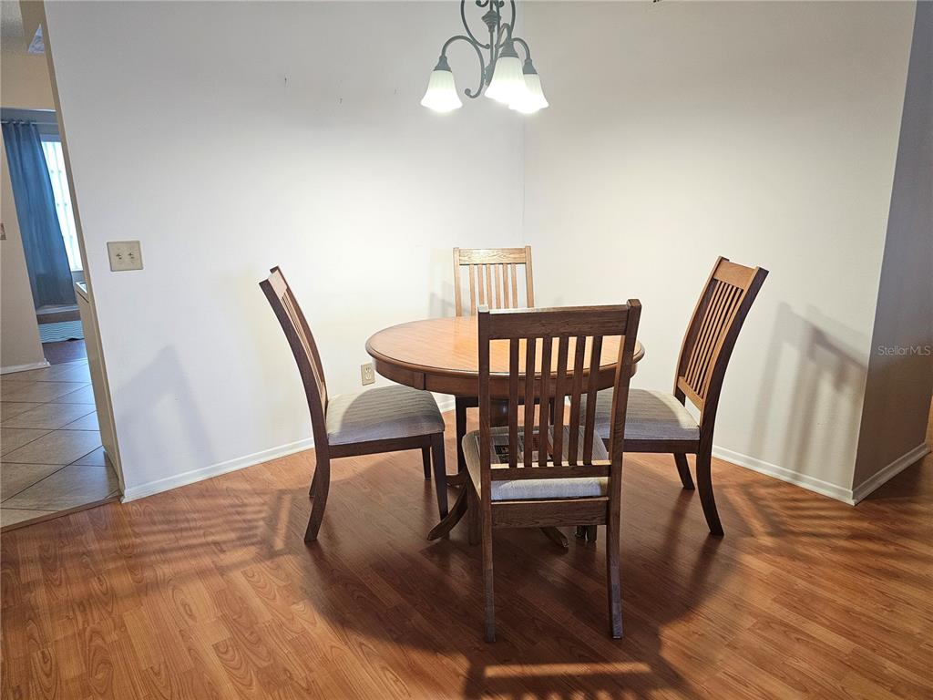 A dining area features a round wooden table with four chairs under a light fixture — 2469 FRANCISCAN DRIVE UNIT 59, CLEARWATER, FL