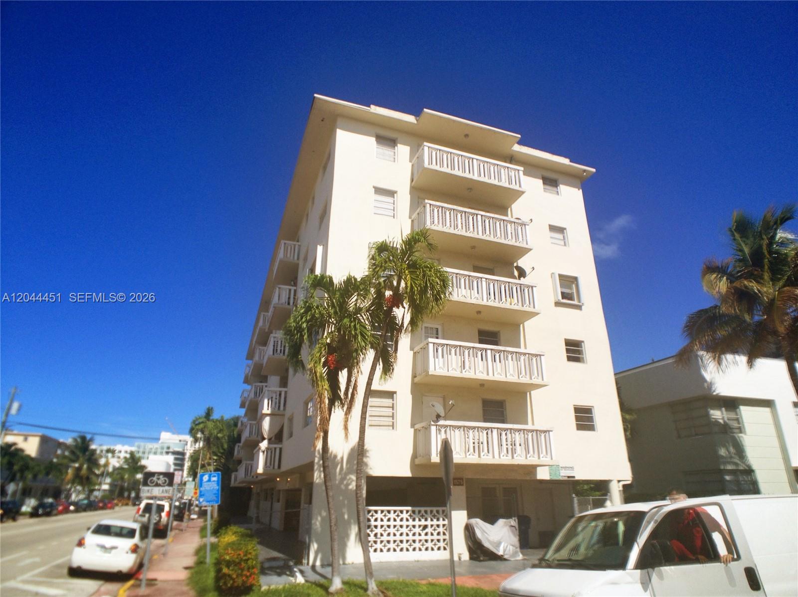 A multi-story cream-colored apartment building stands next to a street with parked cars — 1575 Euclid Ave # 305, Miami Beach FL 33139, MIAMI BEACH, FL