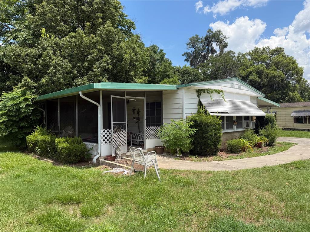 A single-story mobile home features a screened-in porch, white siding, and a concrete walkway — 3209 SE 39TH AVENUE, OCALA, FL