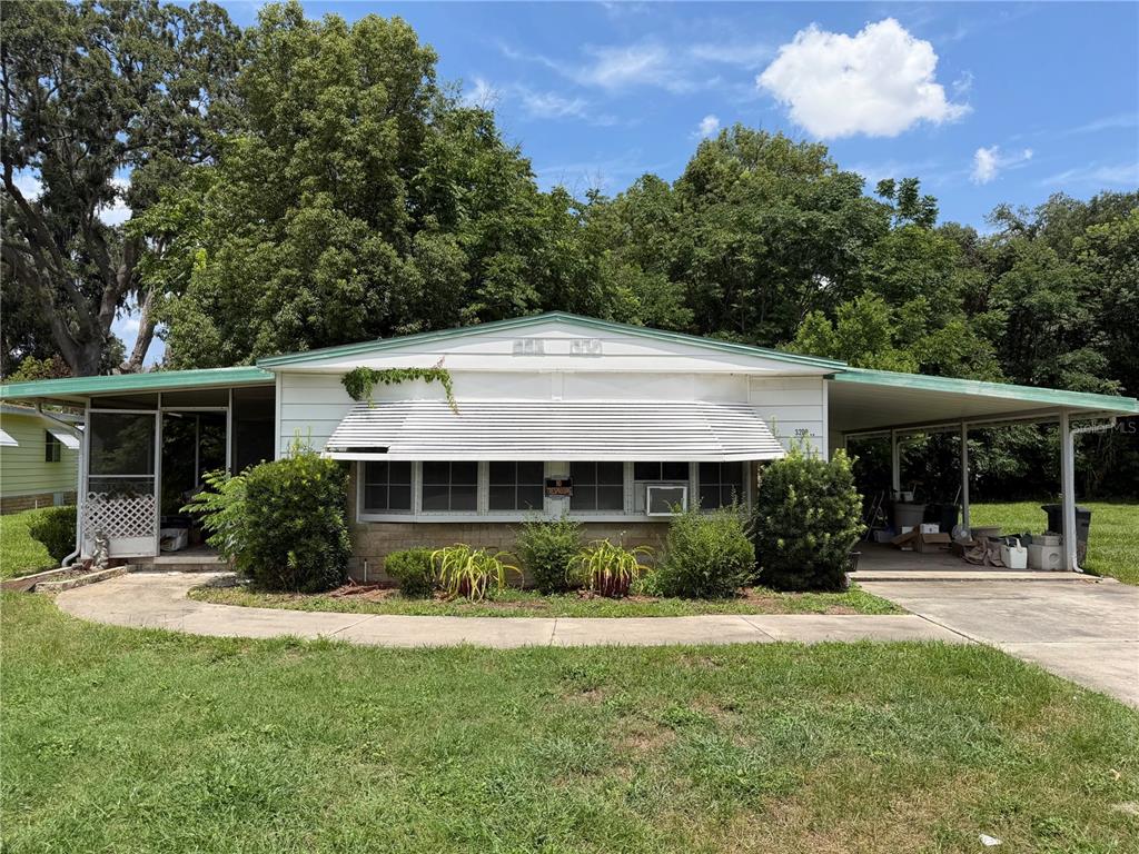 A single-story house with a white exterior, a front awning, and an attached carport — 3209 SE 39TH AVENUE, OCALA, FL