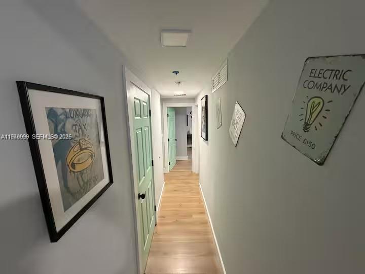 A hallway with light wood flooring, a mint green door, and wall art — 6828 NW 3rd Ave # 1, Miami FL 33150, MIAMI, FL