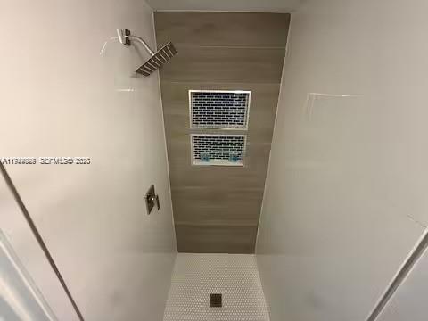 A walk-in shower features white walls, a wood-look tiled back wall, and a rainfall showerhead — 6828 NW 3rd Ave # 1, Miami FL 33150, MIAMI, FL