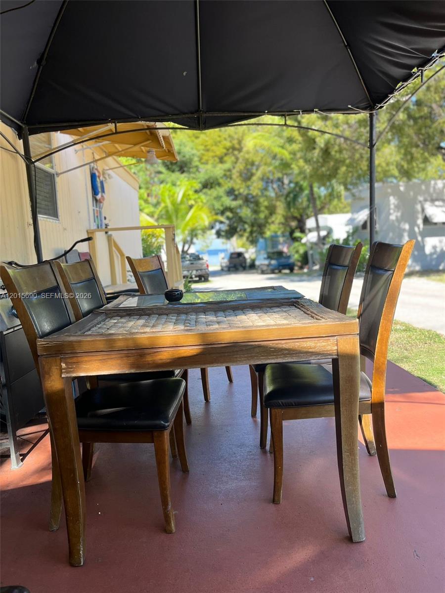 A dining set with a tiled table and four chairs sits under a patio canopy — 103650 Overseas Hwy, Key Largo FL 33037, KEY LARGO, FL