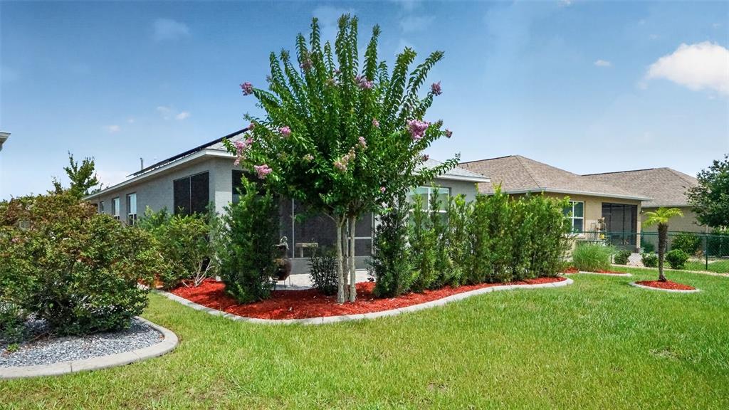 The exterior of a house features a landscaped garden bed with a flowering tree — 8750 SW 76TH STREET ROAD, OCALA, FL