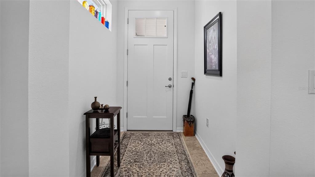 An entryway features a white front door, a patterned rug, and a small wooden table — 8750 SW 76TH STREET ROAD, OCALA, FL