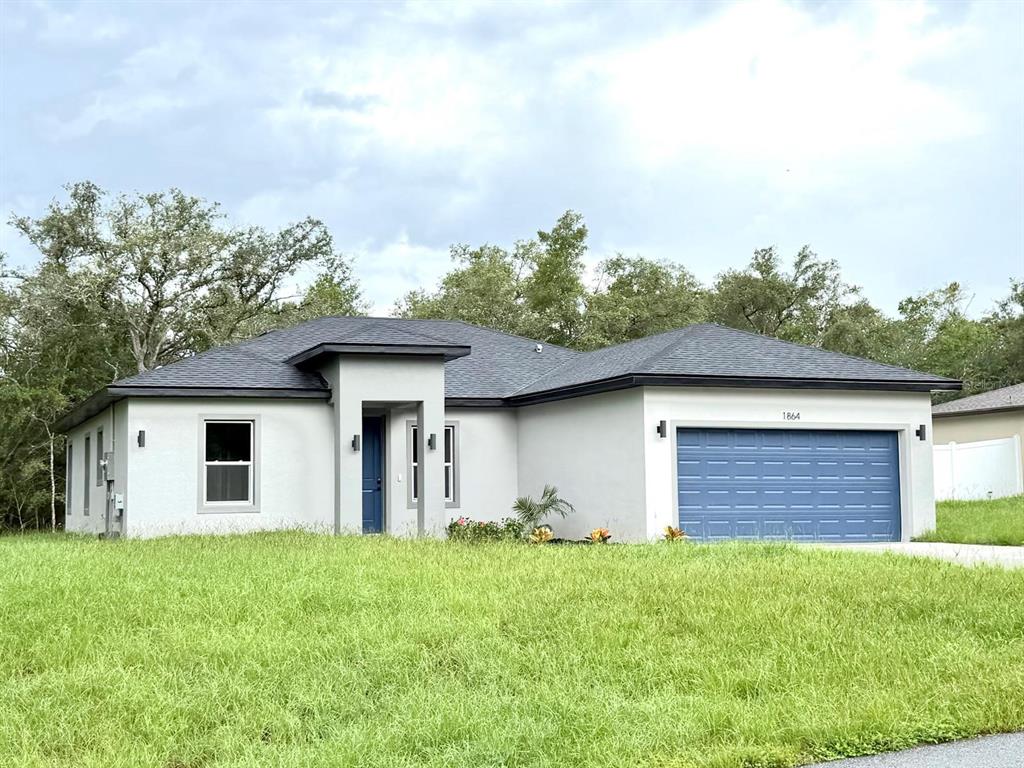 A single-story house with a gray stucco exterior, a blue garage door, and a grassy yard — 1864 W ROSEBORO DRIVE, CITRUS SPRINGS, FL